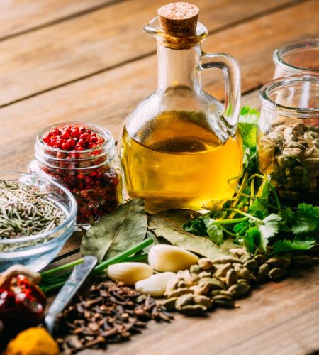 Assorted spices and herbs and bottle of oil placed on wooden tabletop